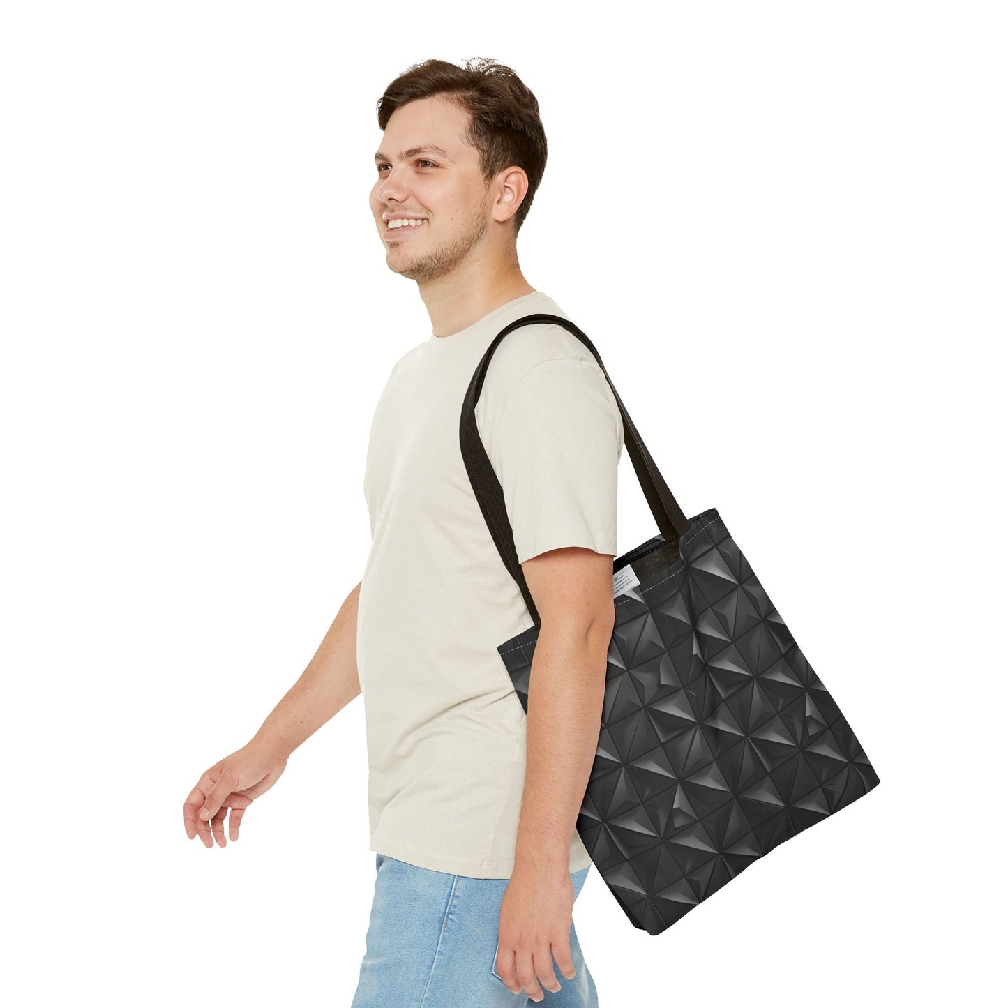 A man is carrying a tote bag with a matte black base embossed with a 3D pyramid tile pattern, with the vertices of each triangle repeating over his left shoulder.