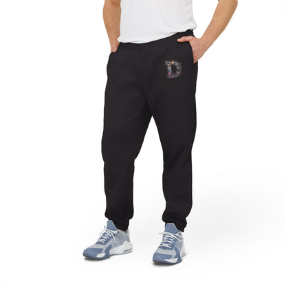 A man wearing Black joggers featuring a bold "D" design on the front with a retro-futuristic and holographic vibe, with his hands in his pockets.