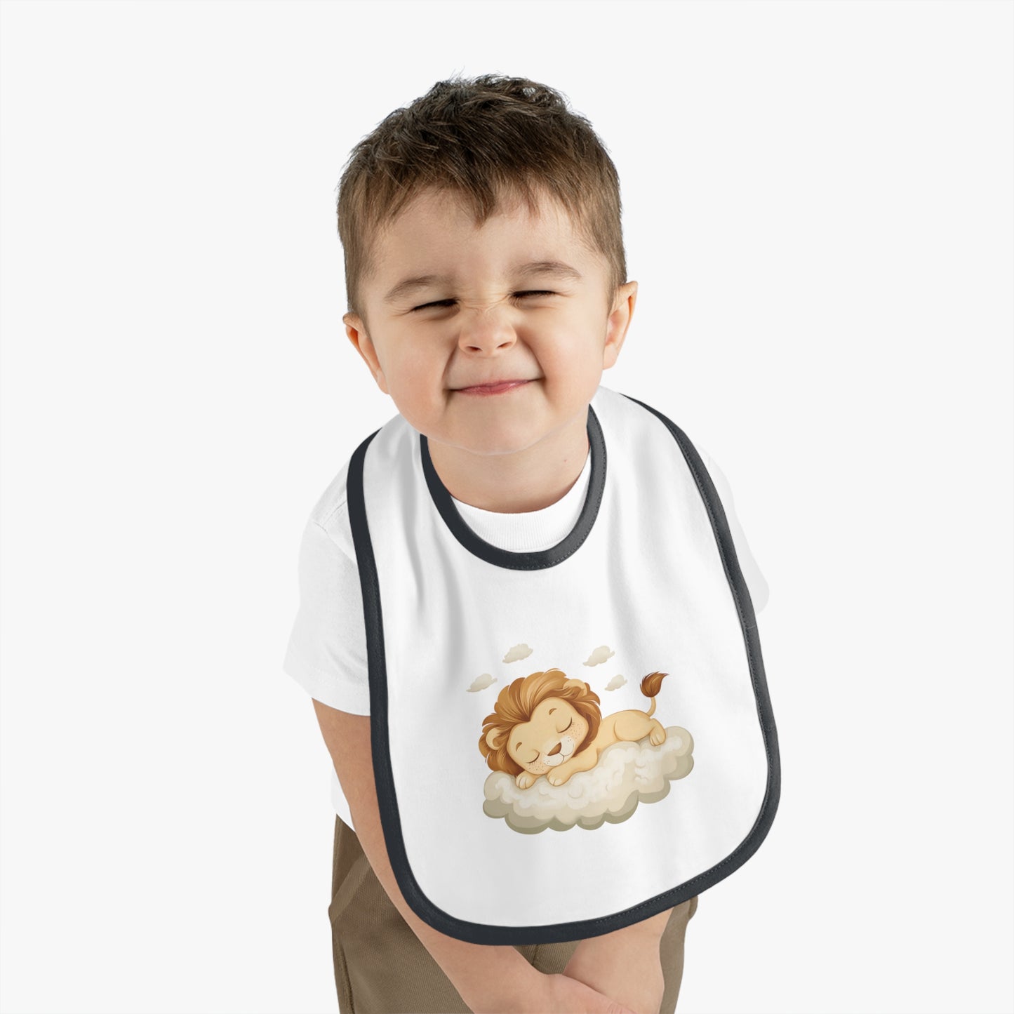 A baby boy wearing an adorable bib with a black-colored trim and a white base, featuring a design of a cute lion peacefully sleeping on a fluffy cloud.