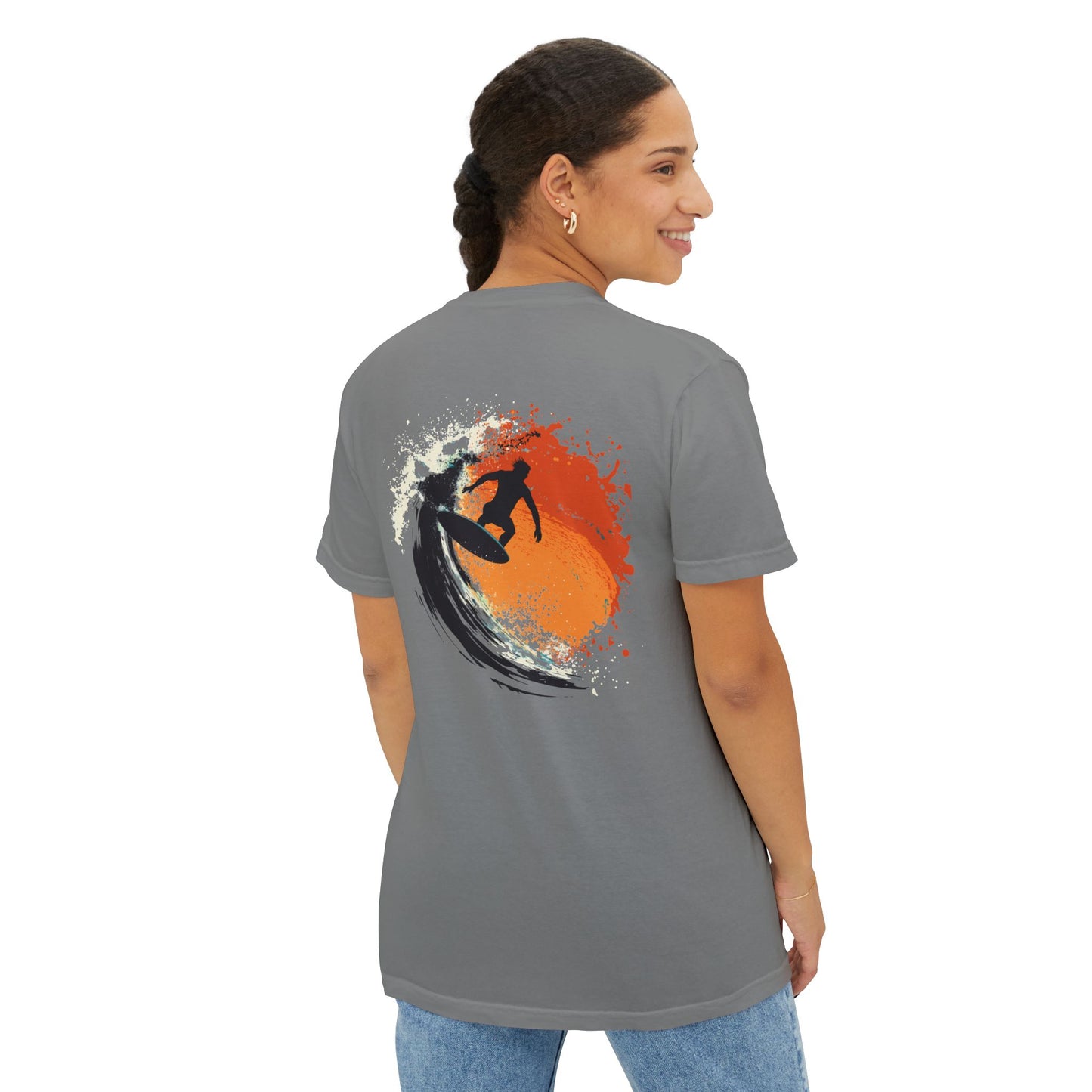 A woman wearing a grey T-shirt featuring a design of a surfboard, waves, and a surfer on the back.