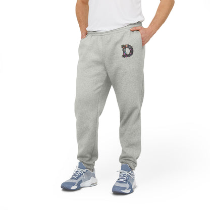 A man wearing Grey Heather joggers featuring a bold "D" design on the front with a retro-futuristic and holographic vibe, with his hands in his pockets.