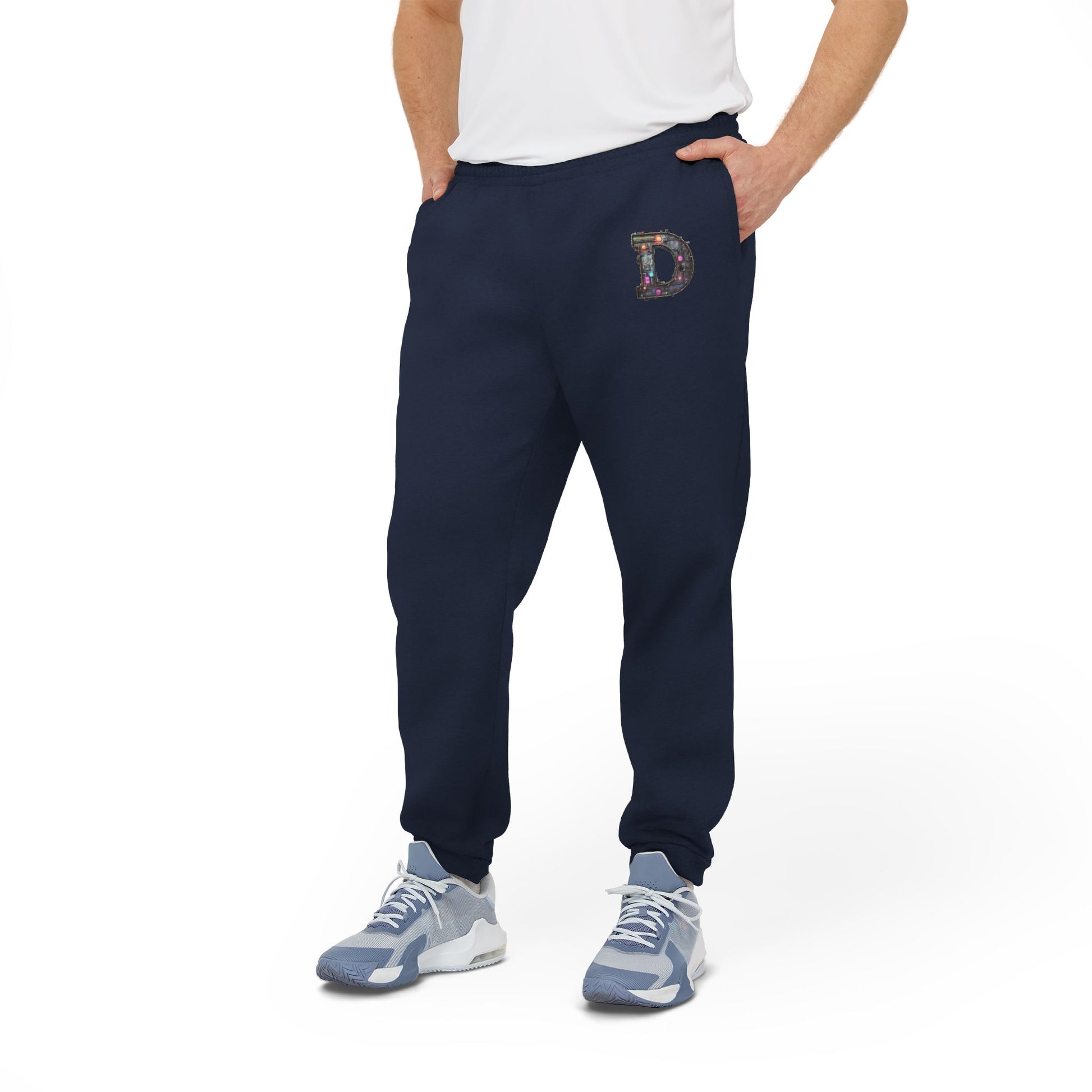 A man wearing Collegiate Navy joggers featuring a bold "D" design on the front with a retro-futuristic and holographic vibe, with his hands in his pockets.