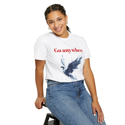 A woman sitting on a chair, wearing a unisex White garment-dyed T-shirt featuring glitch art depicting a majestic phoenix rising, fragmented in navy and white digital distortion.