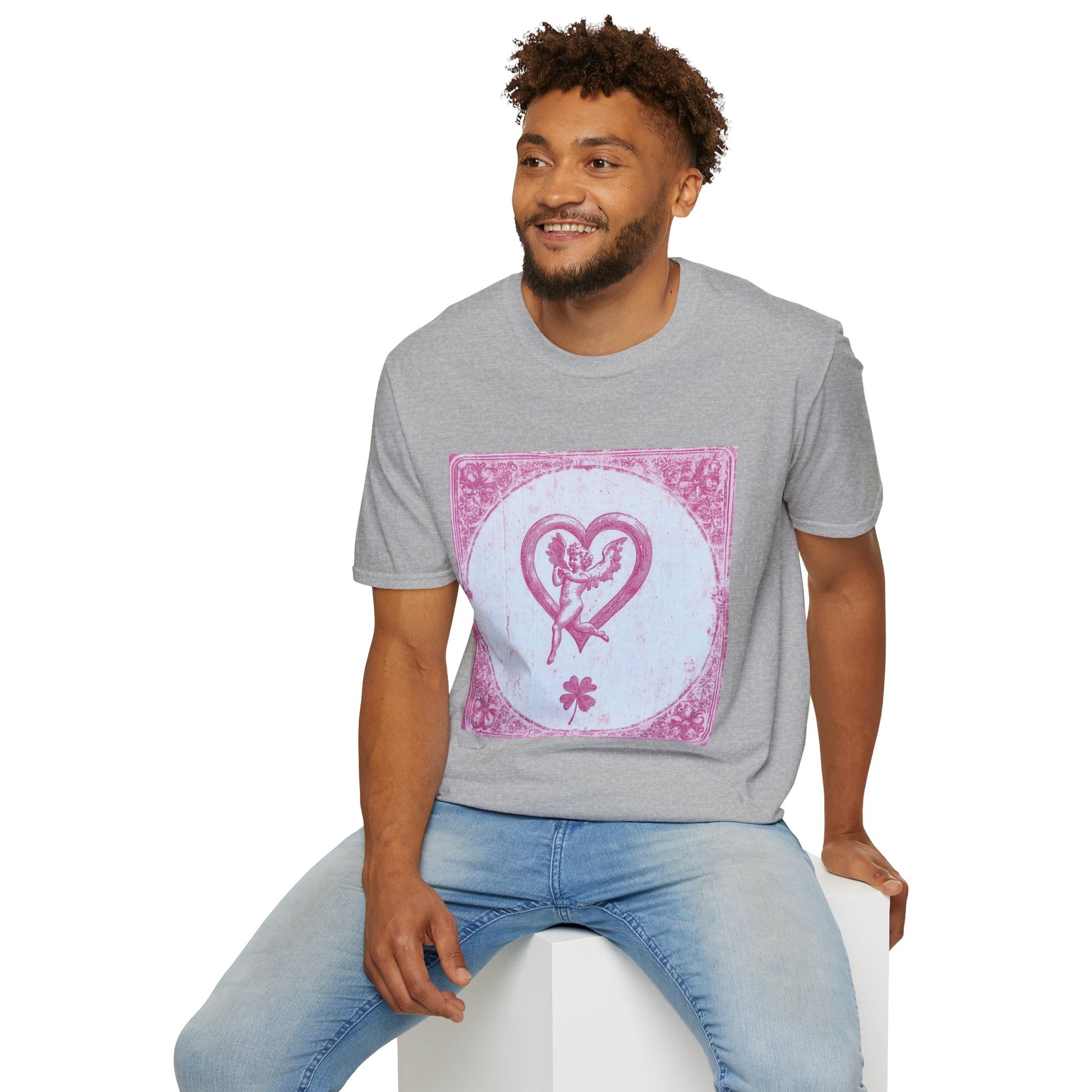 A man sitting on a white box, wearing a Sport Grey T-shirt featuring a vintage 1980s tarot card design with pink risograph and bold gothic typography.
