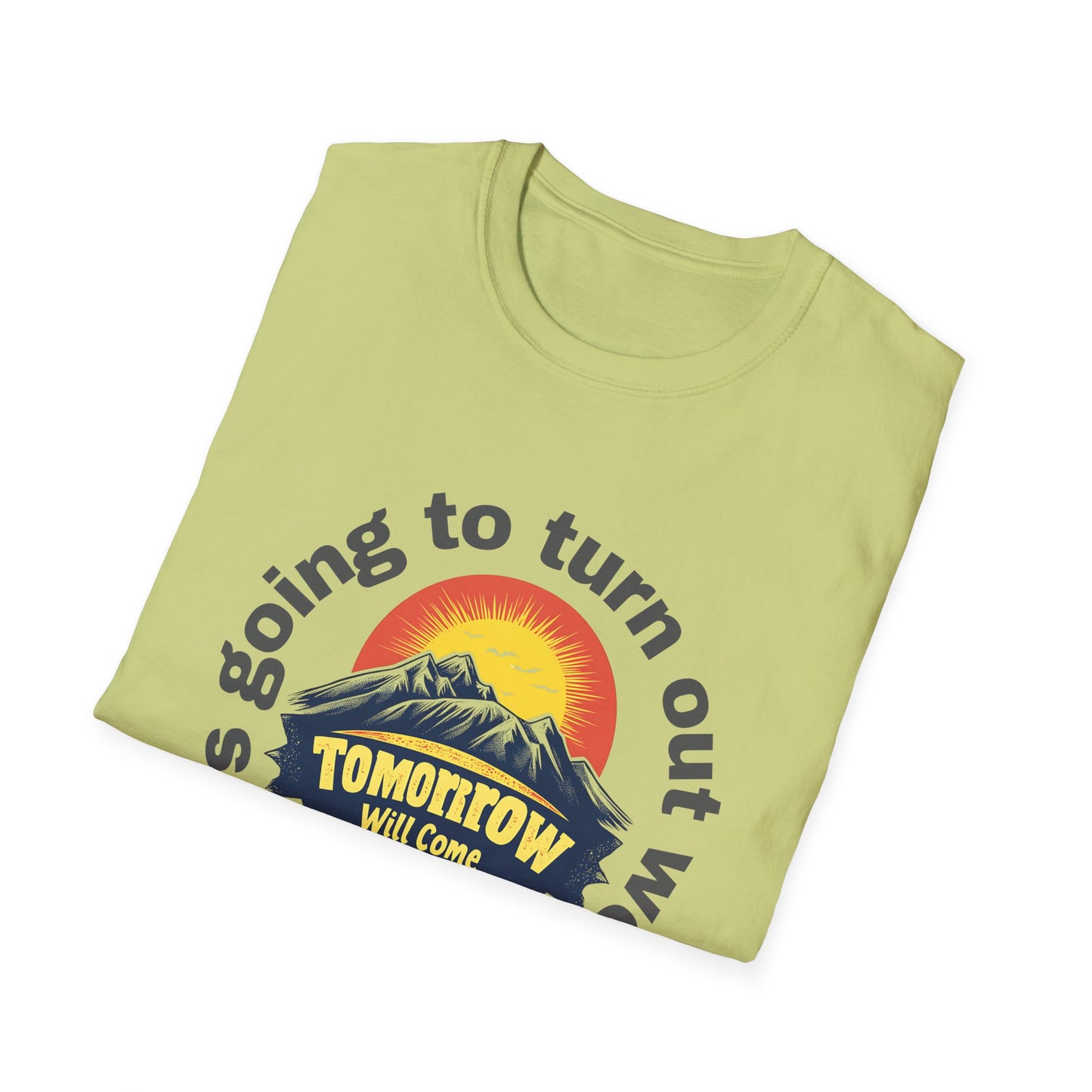 A neatly folded pistachio-colored T-shirt designed with an uplifting message and a warm sunrise graphic.