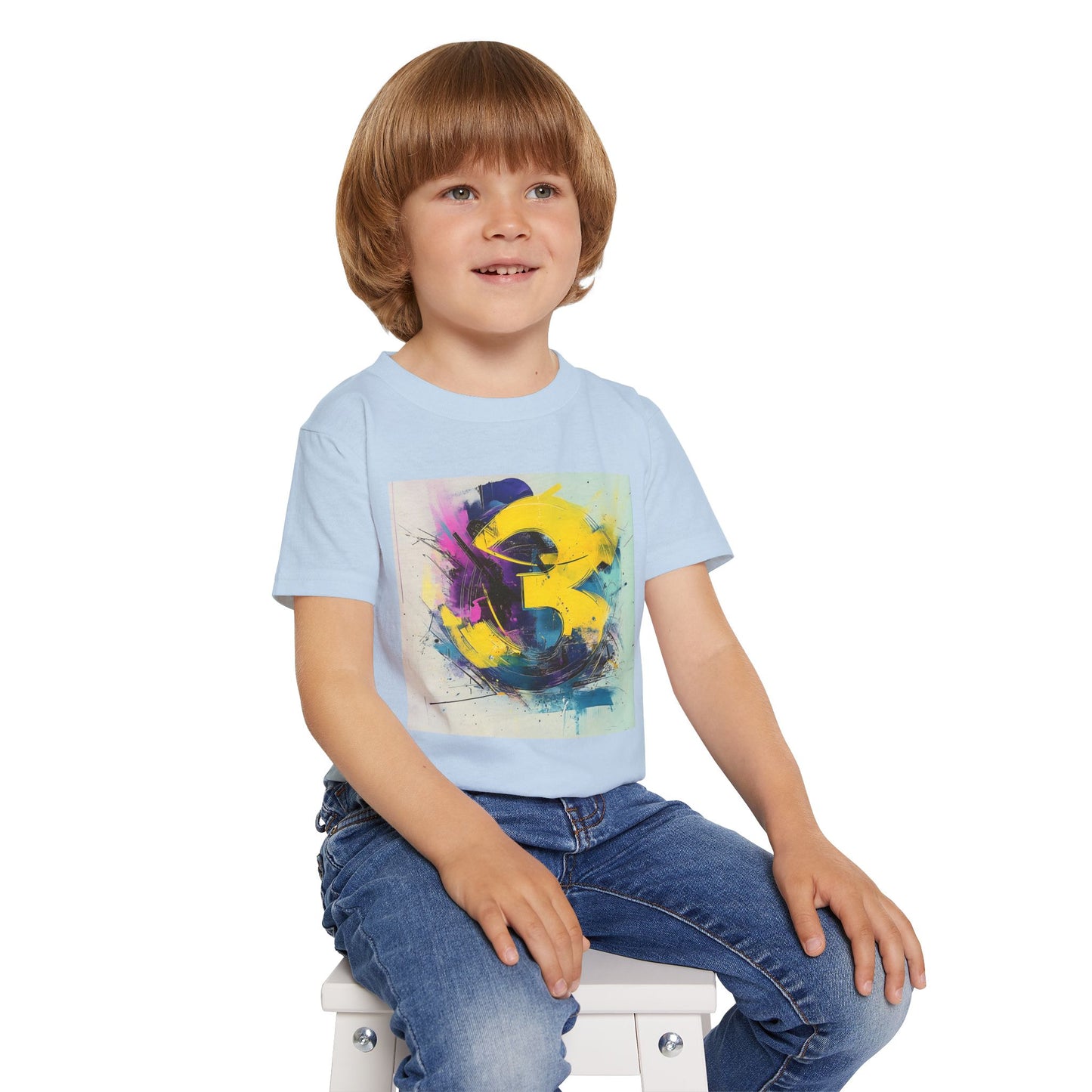 A seated boy wearing a light blue T-shirt featuring a bold and vibrant abstract design with expressive brushstrokes in yellow, purple, and blue.