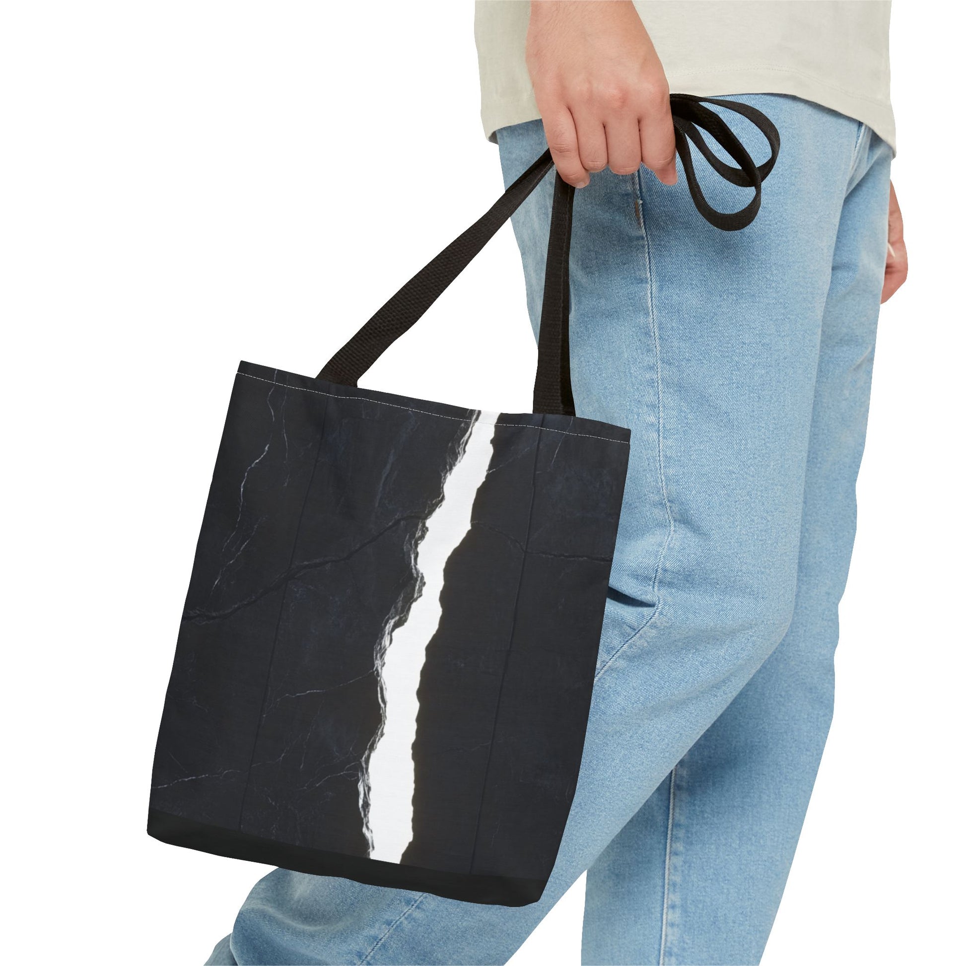 A man holding a Black-handled tote bag with a black wall, white cracks, light shining through, and a central vertical rock.