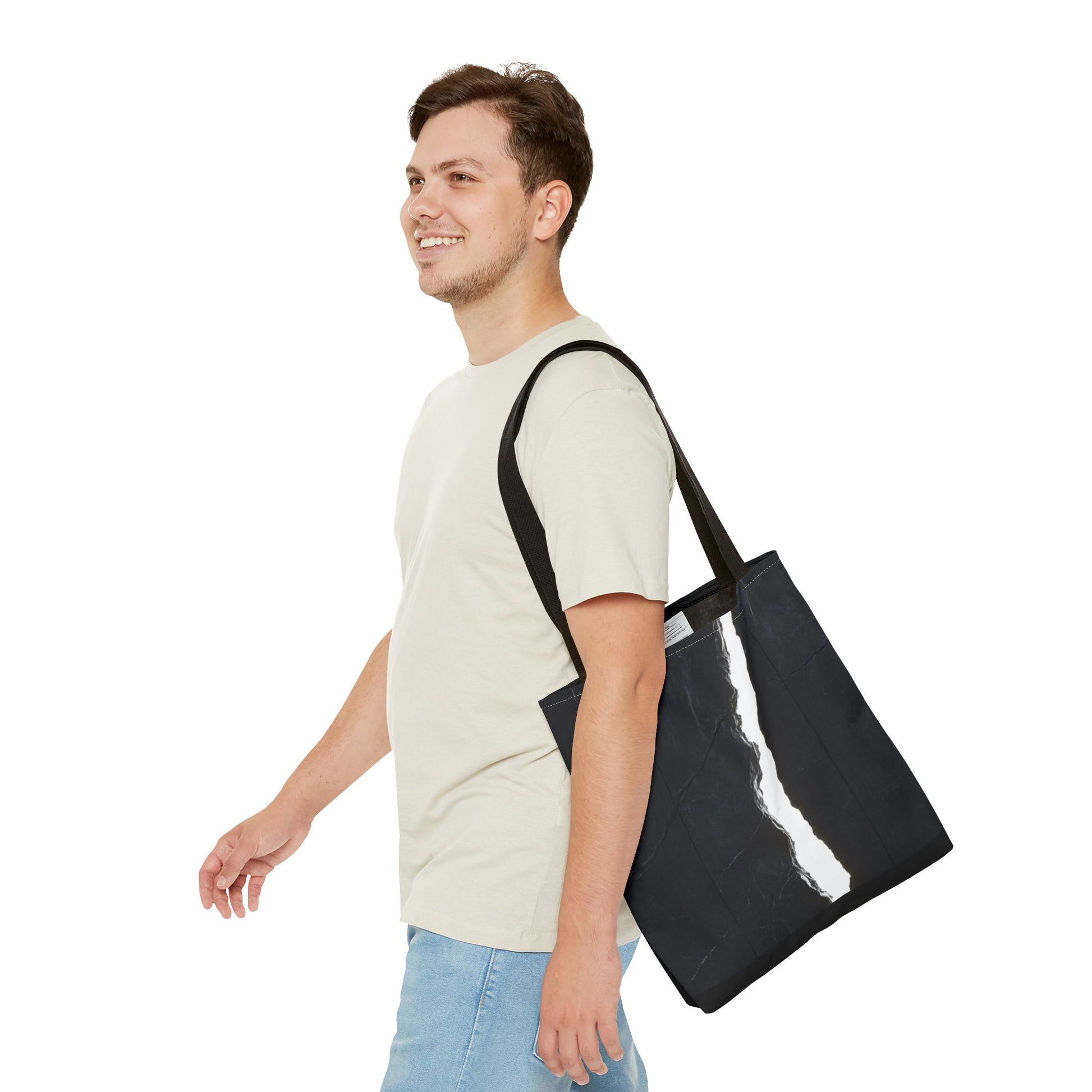 A man carrying a Black-handled tote bag with a massive black wall, white cracks, light streaming through, and a central black vertical rock.