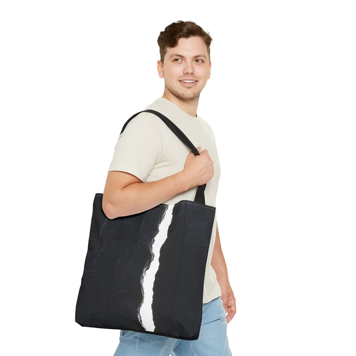 A man wearing a Black-handled tote bag featuring a massive black wall with white cracks and light streaming through, with a central black vertical rock.