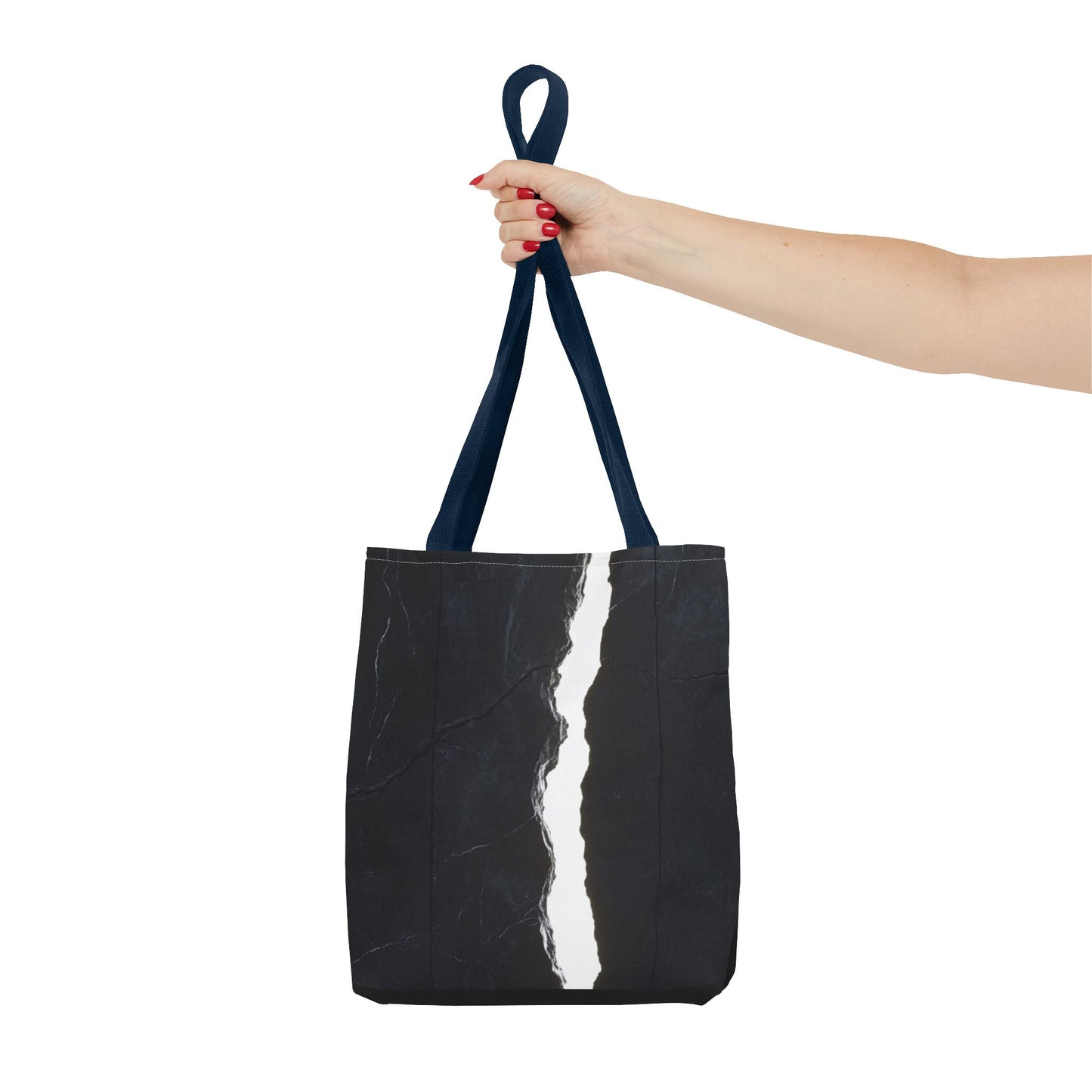 Holding a Navy-handled tote bag with a massive black wall, white cracks, light streaming through, and a central black vertical rock.
